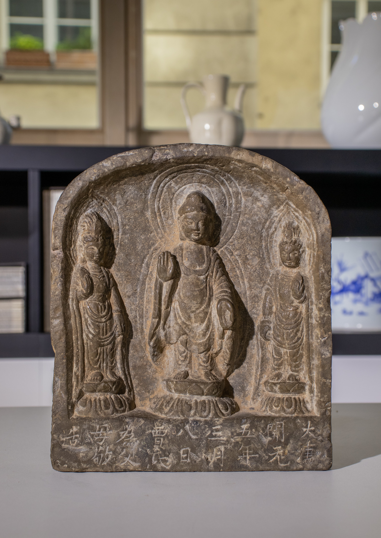 A SANDSTONE 'BUDDHIST TRIAD' STELE, TANG DYNASTY, DATED 717